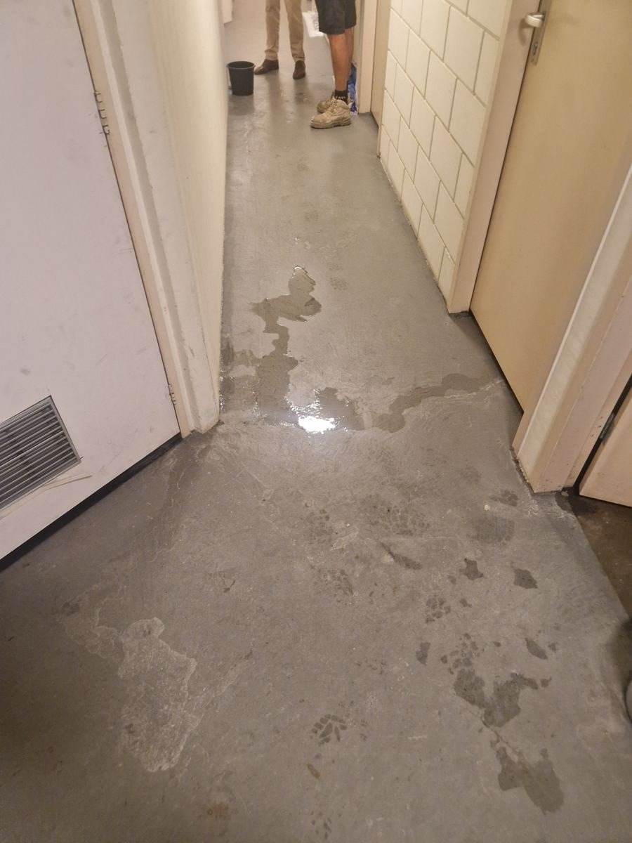 Water op de vloer van een gang in een appartementengebouw